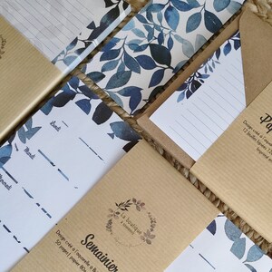Peut inclure: Plusieurs articles de papeterie avec des motifs de feuilles à l'aquarelle bleues et blanches. On y trouve des blocs-notes, des agendas hebdomadaires et du papier ligné. Le texte "Semainier" est visible sur l'un des articles.