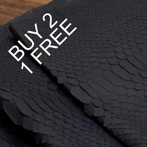 May include: A piece of matte black material featuring a textured snakeskin pattern with overlapping scales. The text BUY 2 GET 1 FREE is printed in white in the upper left corner of the image, angled diagonally across the surface of the material.