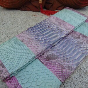 Pu&ograve; includere: Una pochette in pelle di serpente a righe, di colore viola e turchese.