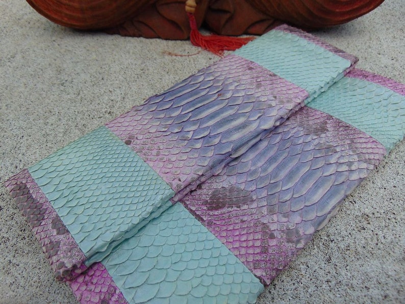 Pu&ograve; includere: Una pochette in pelle di serpente a righe, di colore viola e turchese.