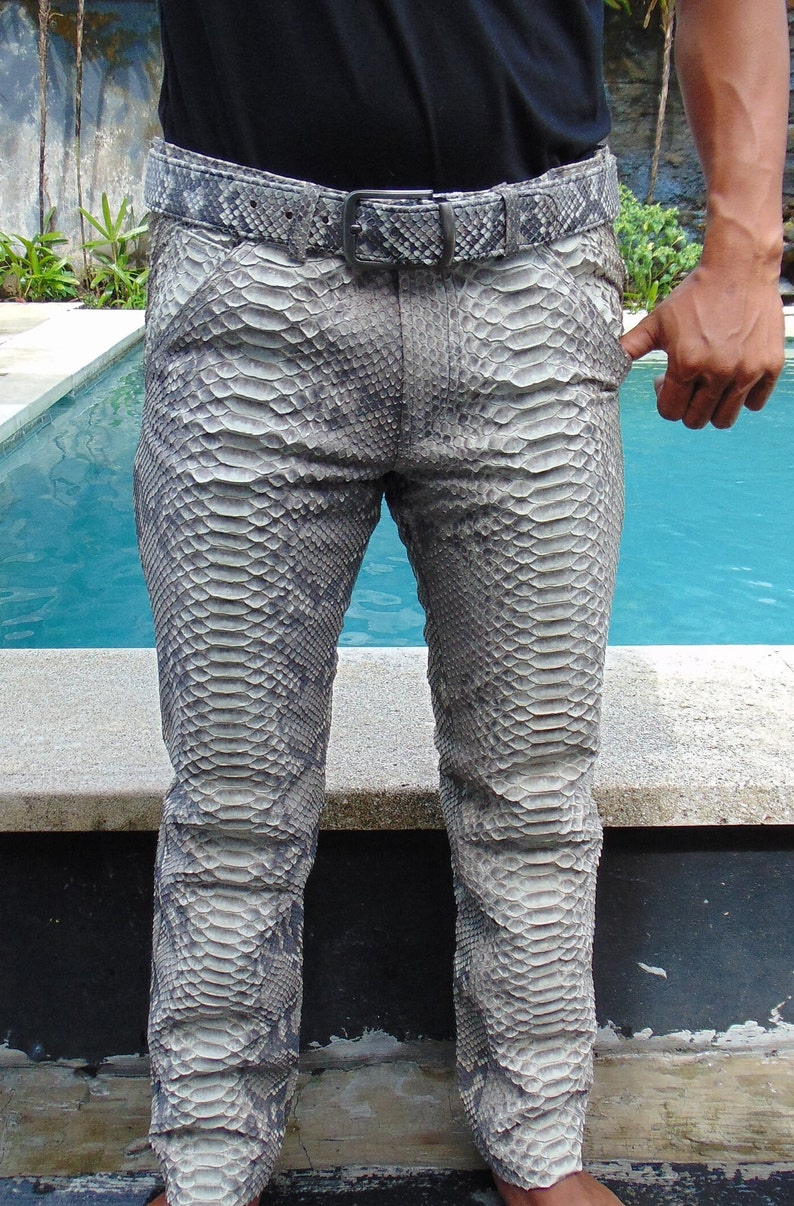 K&ouml;nnte beinhalten: Grau-wei&szlig; gemusterte Hose und passender G&uuml;rtel mit Schlangenmuster. Die Hose hat ein klassisches F&uuml;nf-Taschen-Design und ein gerades Bein. Der G&uuml;rtel hat eine silberfarbene Schnalle. Die Person tr&auml;gt ein schwarzes Hemd.