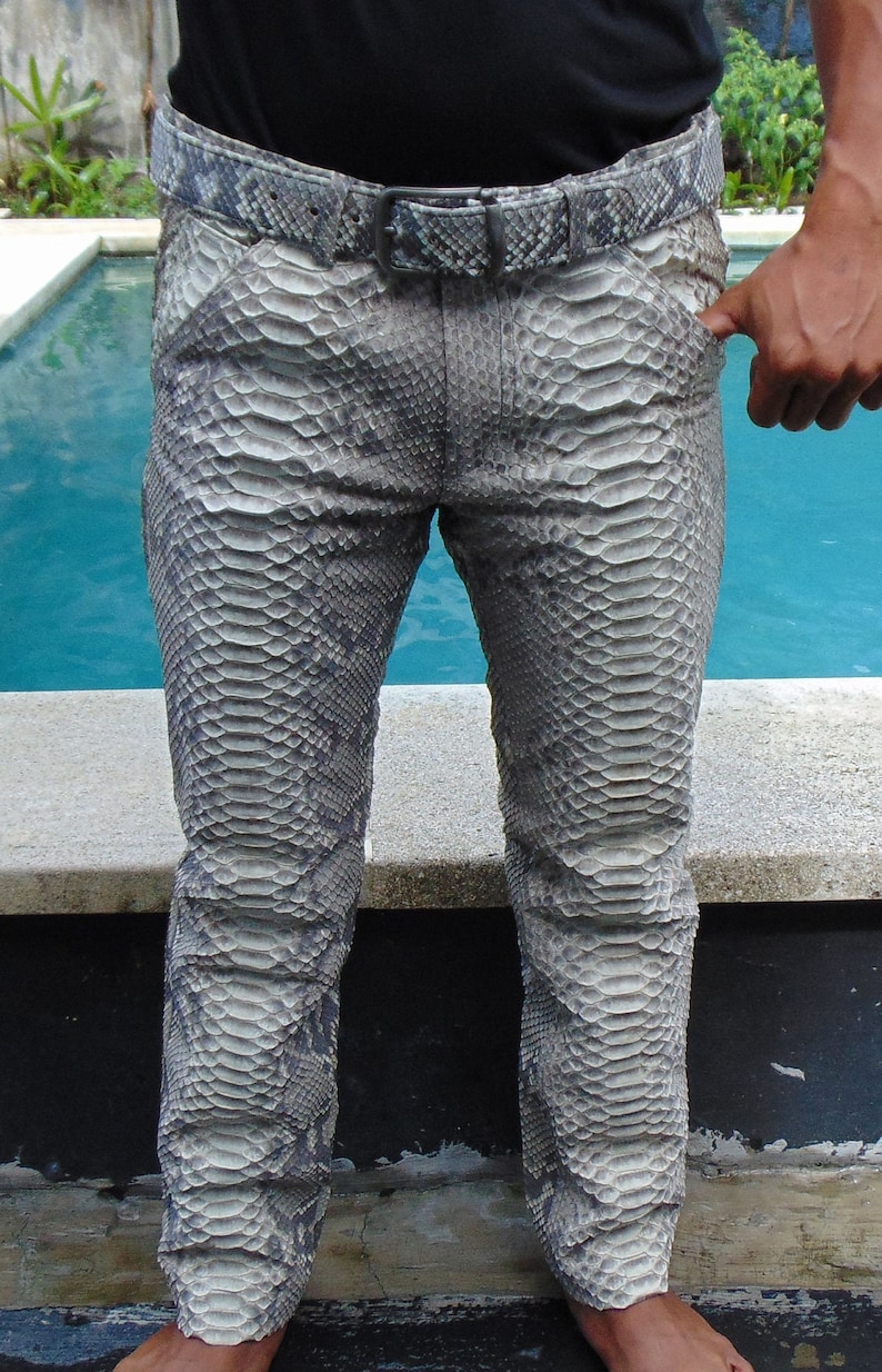 K&ouml;nnte beinhalten: Grau-wei&szlig; gemusterte Hose mit Schlangenleder-Optik und passendem G&uuml;rtel. Die Hose hat ein klassisches F&uuml;nf-Taschen-Design und einen geraden Beinverlauf. Der G&uuml;rtel hat eine silberne Schnalle. Die Hose besteht aus einem Material, das die Textur von Schlangenleder nachahmt.