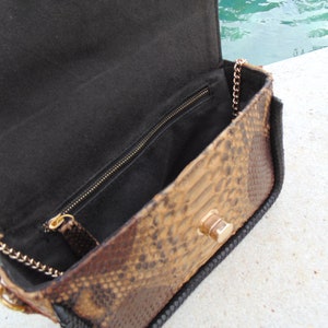 Peut inclure: Un petit sac &agrave; main en peau de serpent marron avec une doublure en tissu noir et une bandouli&egrave;re en cha&icirc;ne dor&eacute;e.