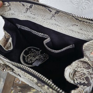 Peut inclure: Un sac &agrave; main en peau de serpent beige et marron avec une doublure en tissu noir et une fermeture &eacute;clair argent&eacute;e. Le sac est ouvert et une cha&icirc;ne argent&eacute;e est visible &agrave; l'int&eacute;rieur.