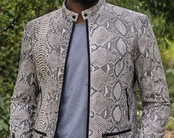 May include: A long-sleeve jacket featuring a grey and white snakeskin pattern, a mandarin collar with a snap button closure, a full-length front zip with black trim, and zipped pockets and cuffs. The jacket is worn over a plain grey t-shirt.