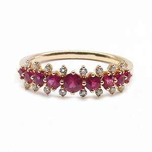 May include: A gold band ring with a row of red rubies and small diamonds set in the band.