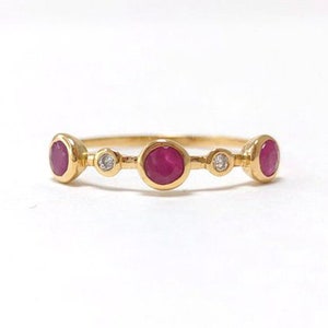 May include: A gold band ring with three ruby stones and two small diamonds.