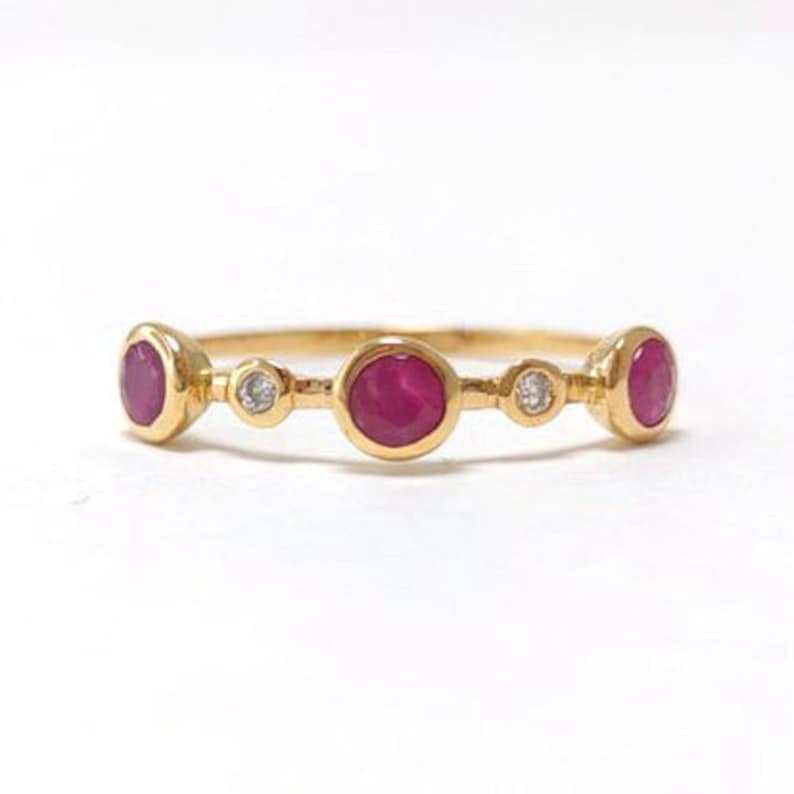 Puede incluir: Un anillo de banda de oro con tres piedras de rub&iacute; y dos diamantes peque&ntilde;os.