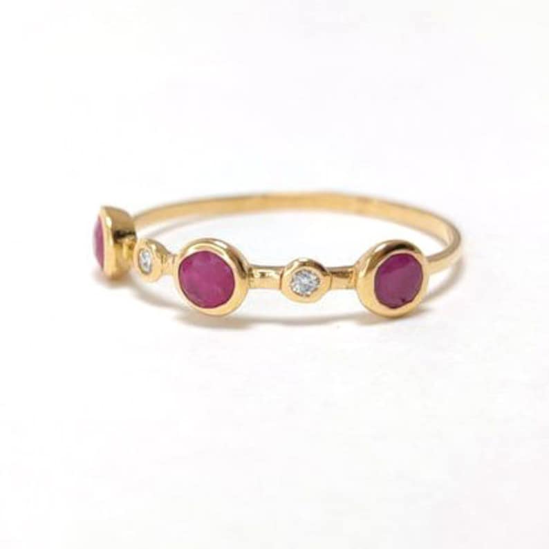 Puede incluir: Un anillo de oro con tres piedras preciosas rosas y dos peque&ntilde;os diamantes. El anillo tiene un dise&ntilde;o delicado y ser&iacute;a un hermoso regalo.