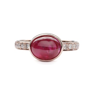 May include: A rose gold ring with a cabochon ruby and a band of small diamonds.