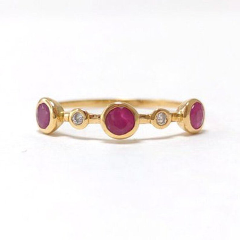 Puede incluir: Un anillo de banda de oro con tres piedras de rub&iacute; y dos diamantes peque&ntilde;os.