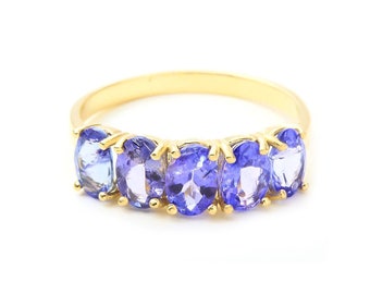 May include: A gold band ring with five oval-shaped blue gemstones.