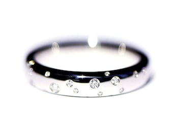 May include: A polished silver ring with multiple small, clear gemstones embedded in the band. The gemstones vary in size and are evenly spaced around the ring, creating a sparkling effect. The ring is set against a bright white background.