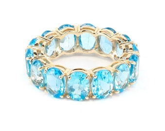 Puede incluir: Un anillo de banda de oro con una fila de piedras azules ovaladas.