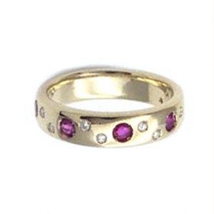 Puede incluir: Un anillo de banda de oro con una fila de piedras de rubí y diamantes alternas.