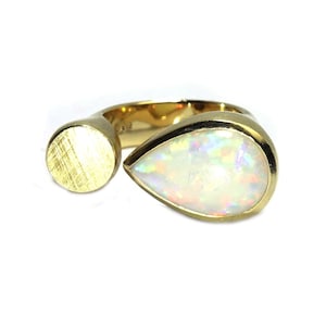 May include: A gold ring with a teardrop-shaped opal gemstone and a round, textured gold band.