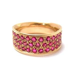 May include: A gold band ring with a wide band set with small red ruby stones.