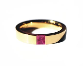 Puede incluir: Un anillo de banda de oro con una piedra preciosa de rubí de forma cuadrada engastada en el centro.