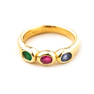 May include: A gold ring with three oval-shaped gemstones: a green emerald, a red ruby, and a blue sapphire.