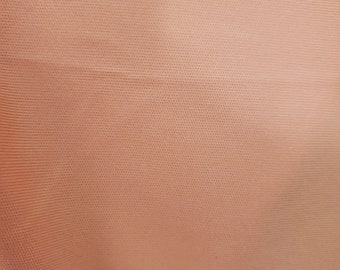 Może przedstawiać: Zbliżenie na tkaninę w kolorze brzoskwiniowym z fakturowanym wzorem tkanym.