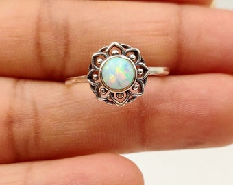 May include: A silver ring with a white opal gemstone set in a delicate floral design.