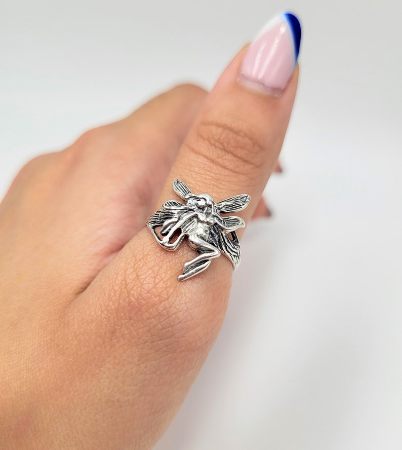 May include: A silver ring featuring a detailed fairy design with outstretched wings.