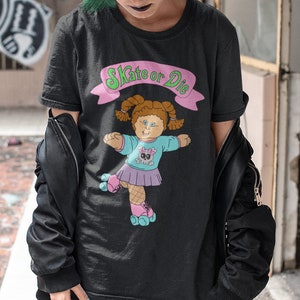 May include: A black t-shirt with a graphic of a cartoon girl on roller skates. The graphic says "Skate or Die".