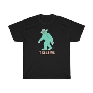 May include: Black t-shirt with a green monster graphic and the text "I BELIEVE" in pink.