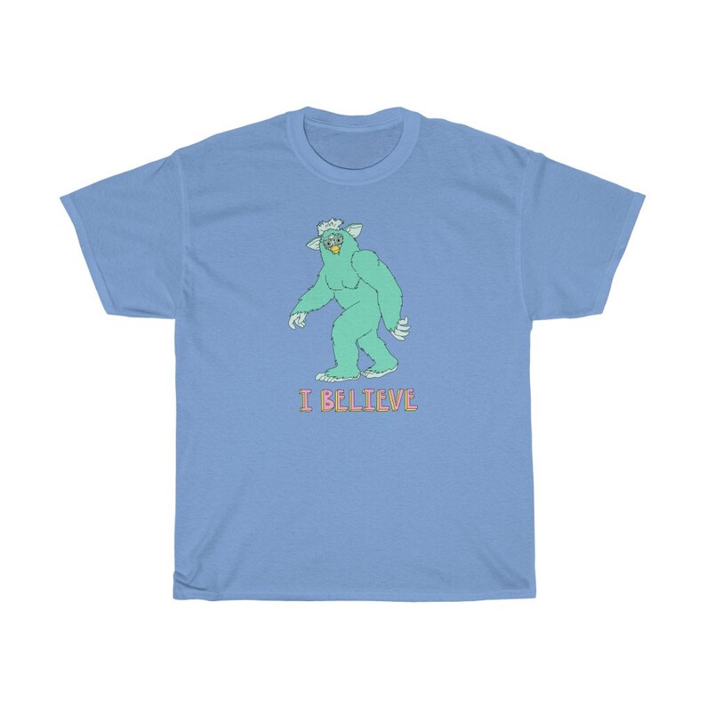 May include: A light blue t-shirt with a green cartoon monster walking and the text "I BELIEVE" in pink.