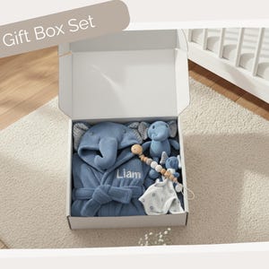 A gift box containing a blue elephant robe, a blue elephant plush toy, and a blue elephant pacifier.