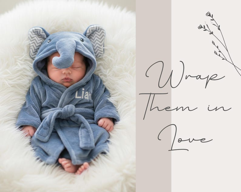 A sleeping baby dressed in a blue elephant-themed robe is pictured on a white fur-covered surface.