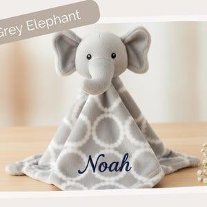 A grey elephant plush toy with the name "Noah" embroidered on it, sitting on a wooden surface.
