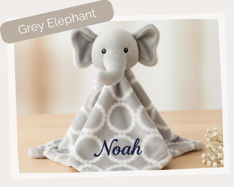 A grey elephant plush toy with the name "Noah" embroidered on it, sitting on a wooden surface.