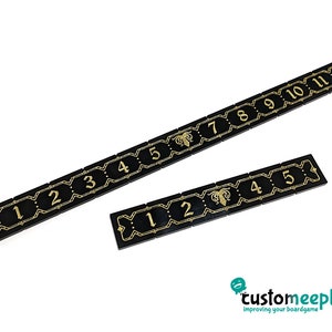 Puede incluir: Dos piezas de pista numeradas negras con números dorados y un diseño dorado. Los números en la pieza de pista superior son del 1 al 11. Los números en la pieza de pista inferior son del 1 al 5.