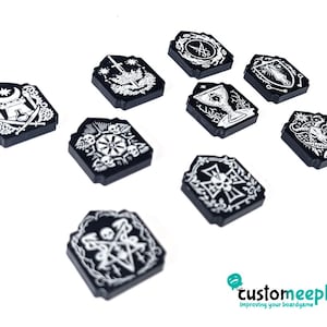 Op de afbeelding: Een verzameling zwarte, rechthoekige speltoken met witte, ingewikkelde ontwerpen. Elk token heeft een uniek symbool, waaronder een kelk, een ster en een schedel. De tokens zijn gerangschikt op een witte achtergrond, wat wijst op een bordspelthema.