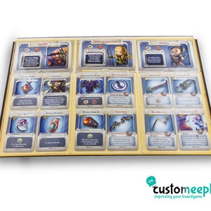 Pu&ograve; includere: Un organizzatore in legno con 12 slot per contenere le carte. Ogni slot ha un inserto in plastica trasparente per proteggere le carte. L'organizzatore &egrave; etichettato con i nomi dei personaggi del gioco, come "Ogdo", "Mangawonder" e "Gary".