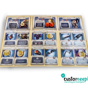 Pu&ograve; includere: Un set di 12 carte da gioco a tema fantasy con illustrazioni di personaggi, armi e oggetti magici. Le carte sono disposte in una griglia su una superficie marrone chiaro. Le carte hanno un bordo dorato e uno sfondo blu.