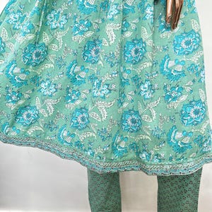 May include: A two-piece outfit featuring a mint green top and pants. The top has a floral pattern in shades of turquoise and white. The pants are a solid mint green with a small, repeating pattern. The outfit is made of a lightweight fabric.