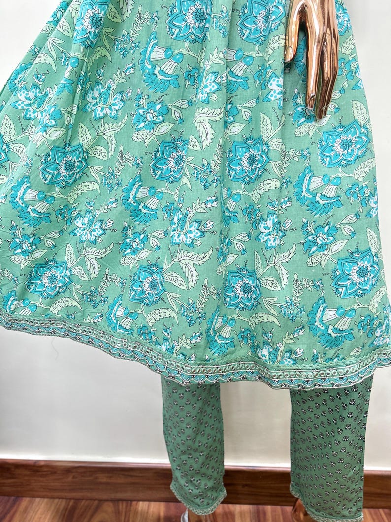 May include: A two-piece outfit featuring a mint green top and pants. The top has a floral pattern in shades of turquoise and white. The pants are a solid mint green with a small, repeating pattern. The outfit is made of a lightweight fabric.