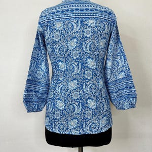 May include: A blue and white floral print long-sleeve shirt with a mandarin collar and a gathered cuff detail.