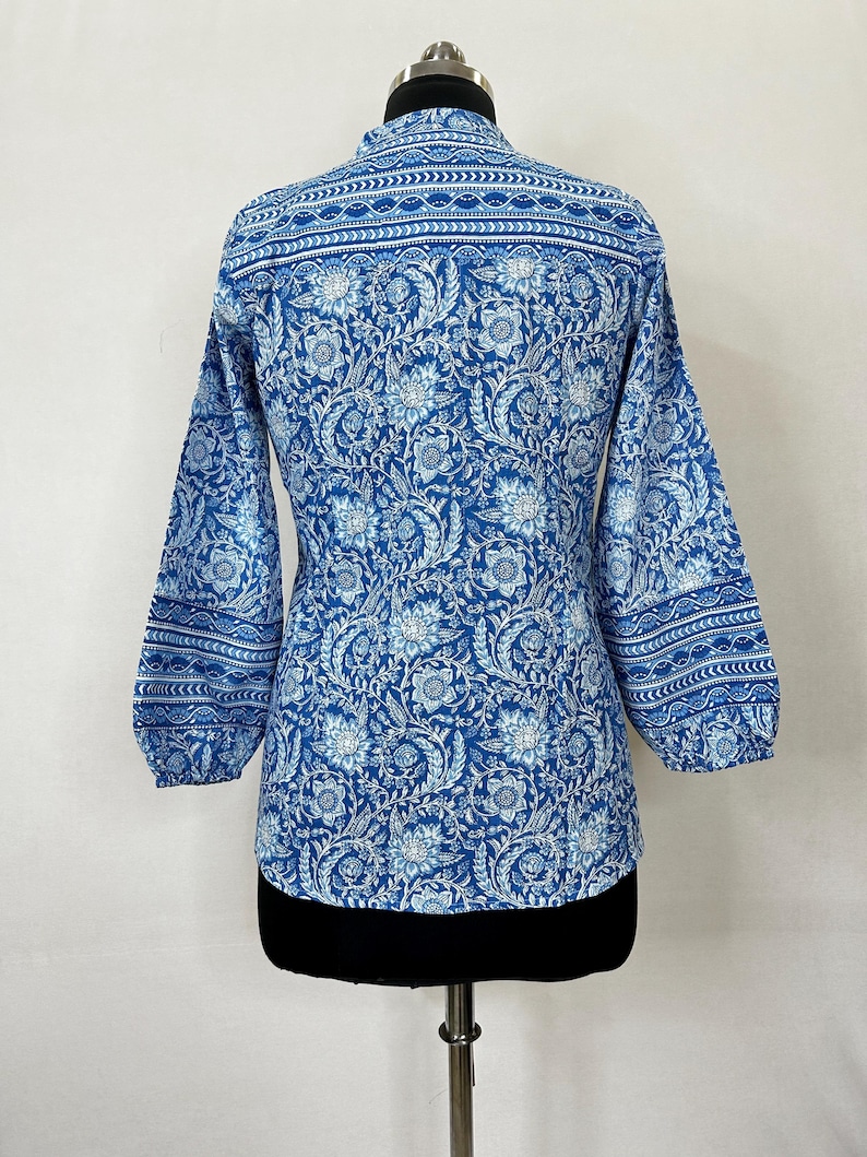 May include: A blue and white floral print long-sleeve shirt with a mandarin collar and a gathered cuff detail.