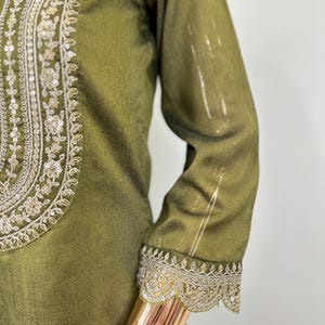 May include: A green tunic with gold embroidery and sequins. The embroidery is around the neckline and the sleeves.