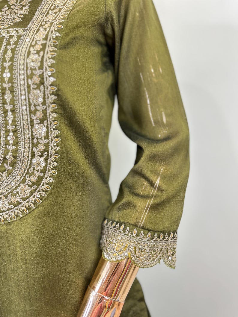 May include: A green tunic with gold embroidery and sequins. The embroidery is around the neckline and the sleeves.