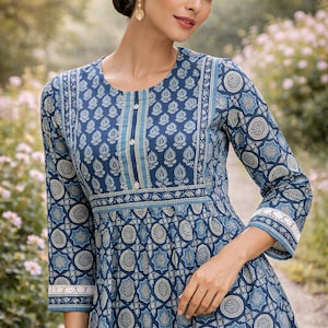 May include: A long-sleeved, blue patterned dress with a round neckline and three-quarter sleeves. The dress features a detailed floral and geometric design in shades of blue and white. The sleeves have a white lace trim.