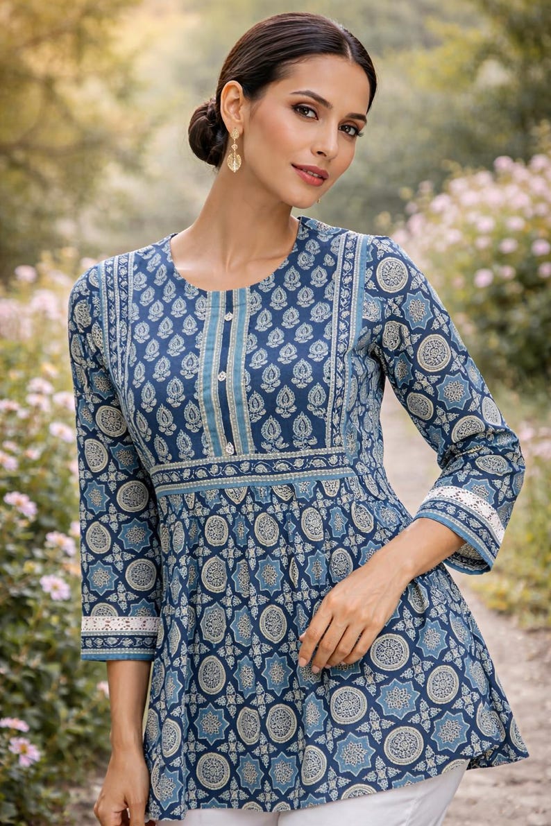 May include: A long-sleeved, blue patterned dress with a round neckline and three-quarter sleeves. The dress features a detailed floral and geometric design in shades of blue and white. The sleeves have a white lace trim.