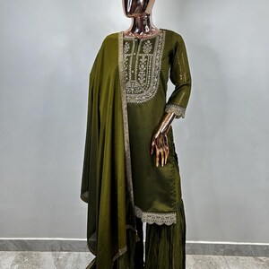 May include: A green embroidered kurta with a matching dupatta and palazzo pants. The kurta has a round neckline and three-quarter sleeves. The dupatta is sheer and has a lace border. The palazzo pants are wide-legged and have a lace trim.