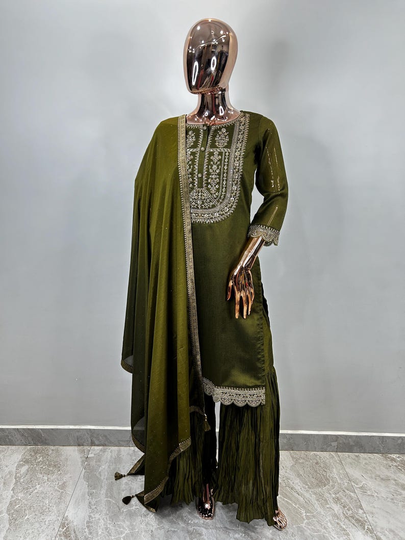 May include: A green embroidered kurta with a matching dupatta and palazzo pants. The kurta has a round neckline and three-quarter sleeves. The dupatta is sheer and has a lace border. The palazzo pants are wide-legged and have a lace trim.