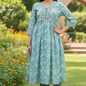 May include: A light green floral print dress and matching pants. The dress has a V-neckline with embroidered detailing and three-quarter sleeves. The outfit is made of a soft, flowing fabric, perfect for a casual occasion.