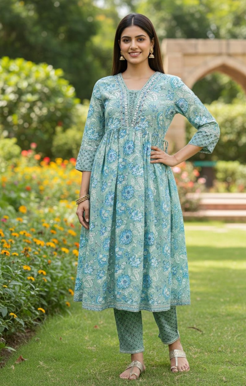 May include: A light green floral print dress and matching pants. The dress has a V-neckline with embroidered detailing and three-quarter sleeves. The outfit is made of a soft, flowing fabric, perfect for a casual occasion.