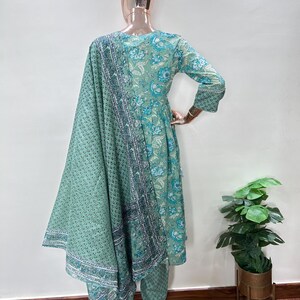 May include: A mint green floral print salwar kameez set. The ensemble includes a long-sleeved tunic, matching pants, and a patterned scarf. The tunic and pants feature a repeating floral pattern in shades of blue and white.